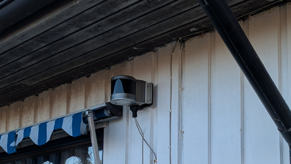 Optical Link mounted on a house wall, under an awning.